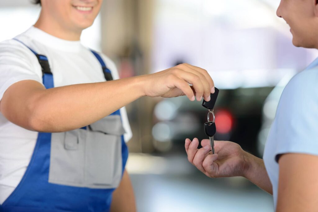 Auto mechanic handing loaner car keys to a women.